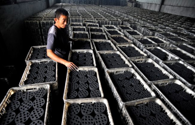 TRABAJADORES CHINOS HACEN BRIQUETAS DE CARBÓN EN UNA FÁBRICA