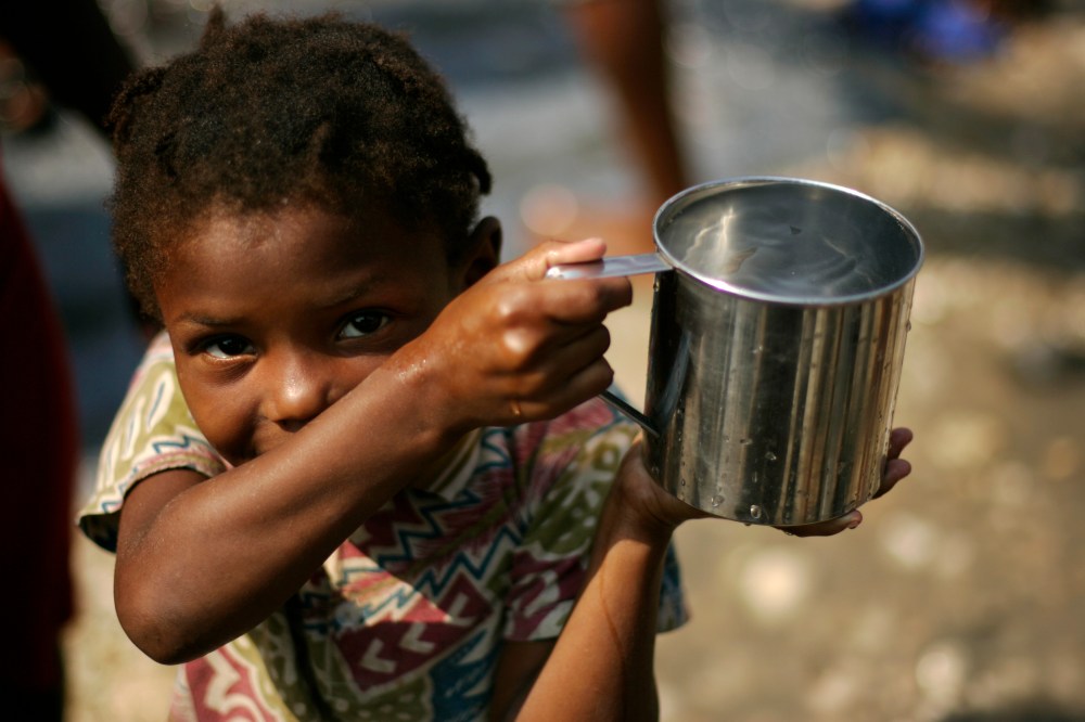 A girl carries a cup with non-potable water on a street in Port-au-Prince